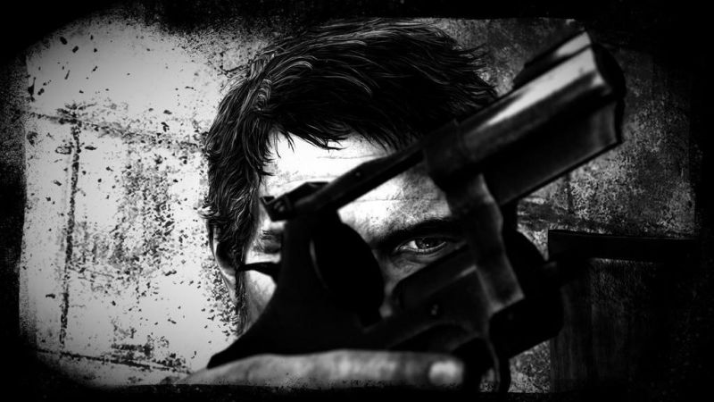 A black and white picture of one of Joel's eyes looking through the empty carriage of a revolver he holds in front of his face.