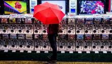 A fan braves bad weather by Gacha machines