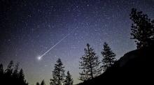 A glowing meteor blasts through the night sky