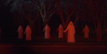 White cloaked cultists wielding knifes shrouded in red light